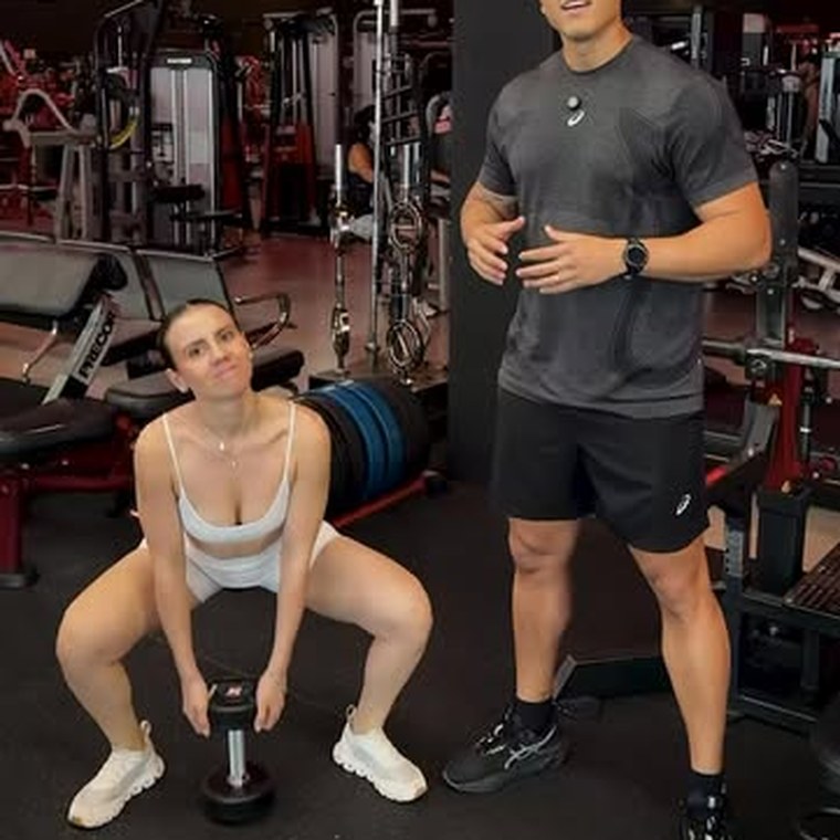 Aluna fazendo agachamento com halter